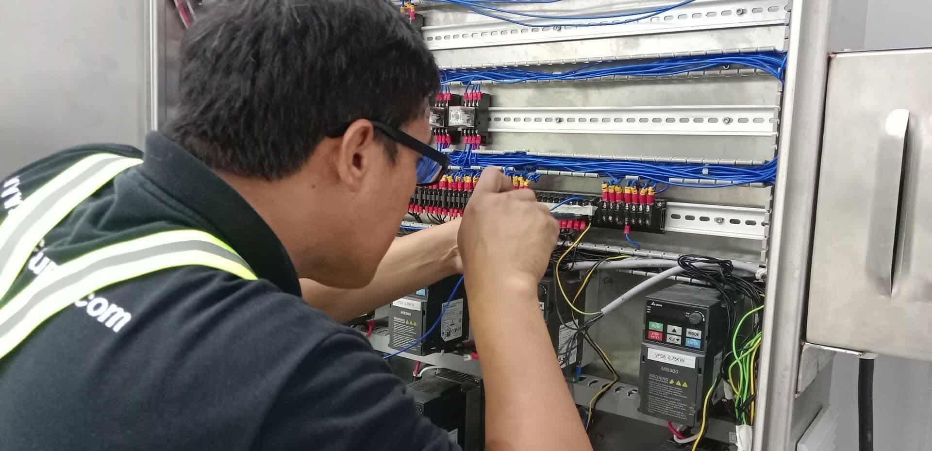 Technician working inside an industrial control panel